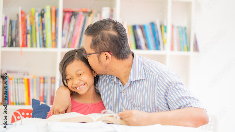 Obraz premium Loving Father Kissing Daughter on Head While Reading Together in Library