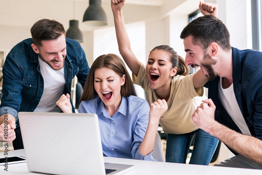 Obraz premium Young professionals cheering at laptop after business achievement