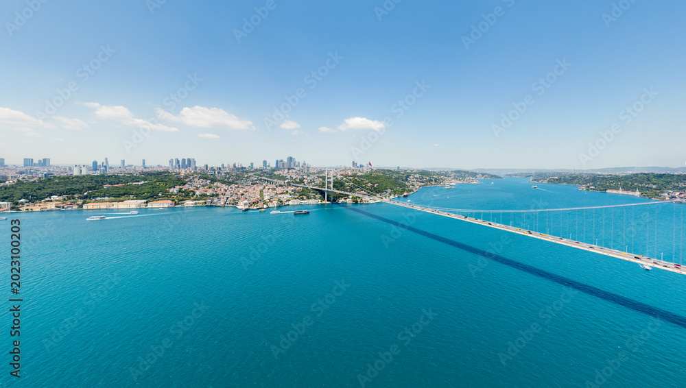Fototapeta premium Istanbul, Turkey. Bosphorus Bridge and empty strait in front of European skyline with modern skyscrapers. Aerial panoramic view of Levent business district at summer midday. Aerial view.
