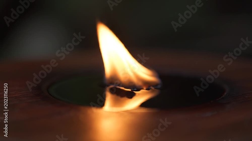 A small flame burns in darkness.