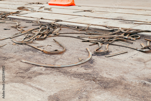 Various metal scraps are scattered on the ground of a construction site. An orange safety cone is positioned nearby, signaling caution and safety during the construction activity