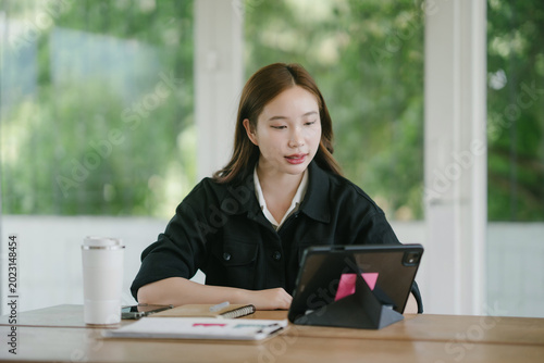 Young Asian woman focusing on work using a digital tablet outdoors, embracing flexible workspace and modern technology