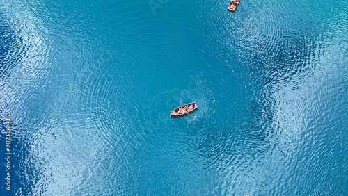 Tranquil blue waters embrace small wooden boats gliding peacefully under sunlit skies