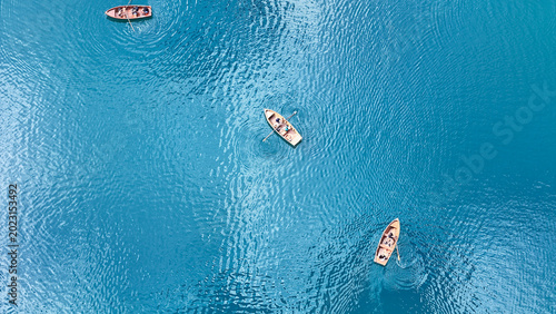 Foto Rows of boats glide gracefully across the tranquil blue waters under the warm su