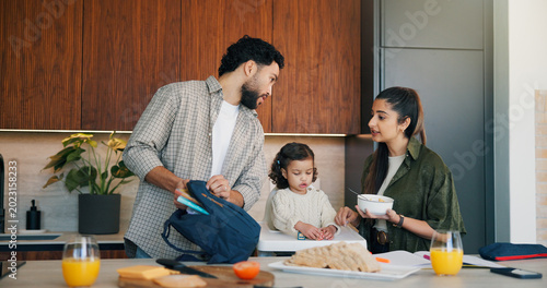 Fotografija Parents, child and pack schoolbag in kitchen for morning routine, breakfast or kindergarten support