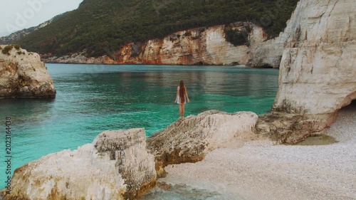 Woman with long hair explores hidden cove and emerald sea cliffs in Kefalonia Greece