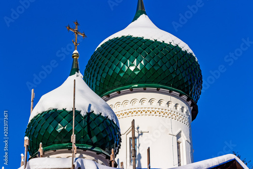 Canvas-taulu Vibrant green onion domes of a Russian Orthodox church, snow-dusted, under construction against a brilliant blue sky