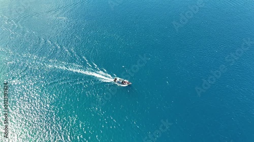 Aerial view of a small motorboat cruising across the crystal clear blue sea
