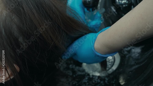 The master of creating hairstyles washes the client's hair in a beauty salon in a special sink for washing her hair.