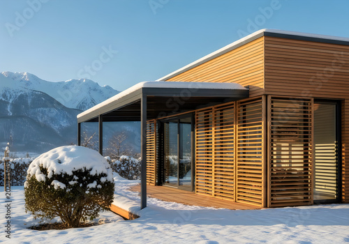 Modern wooden house with snow covered roof and mountain view