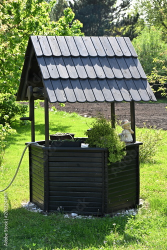 Cuadro en lienzo Wooden Well Structure with Pitched Roof in Charming Rural Garden Setting