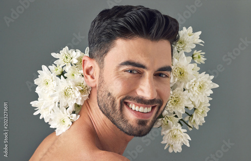 Photography Skincare, flowers and man in studio, natural beauty and portrait with smile on gray background