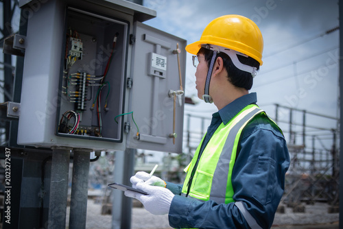 Konstfotografi Engineer inspecting an open electrical cabinet at a substation, checking wiring and control components for maintenance, diagnostics, safety compliance, and grid reliability