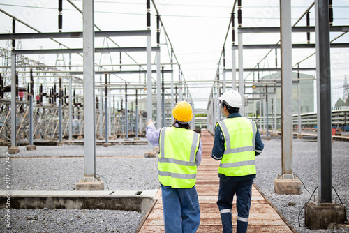 Cuadro en lienzo Engineers walk through an electrical substation during power grid inspection, supporting safety planning, utility maintenance, and high voltage infrastructure reliability