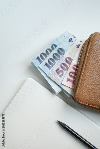 Saving and Planning Money Concept with Notebook, pencil and Taiwan Dollar Bills in Brown Leather Purse.