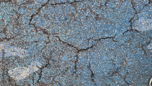 Tableau sur toile Close-up of worn blue-painted asphalt surface with visible cracks and aggregate