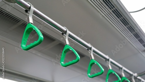 Cuadro en lienzo Row of green plastic hanging hand grips inside public transit