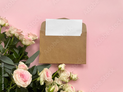kraft envelope with blank card and pink rose on pastel background
