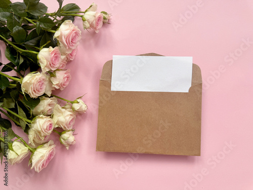kraft envelope with blank card and pink rose on pastel background