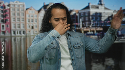 Schilderij op canvas Man pinching nose on a canal street in amsterdam with raised hand and closed eyes; disgust unpleasant smell
