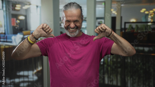 Foto Man flexes forearms with clenched fists inside a hotel building lobby, grinning with eyes closed; triumph joy