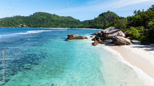 Photos Granite boulders lining a pristine sandy beach with crystal-clear turquoise waters