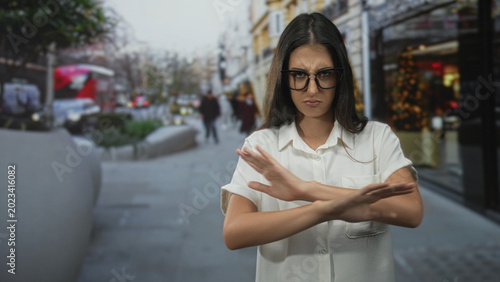 Photos Woman with arms crossed and stern frown on busy city street near shops; setting boundaries frustration