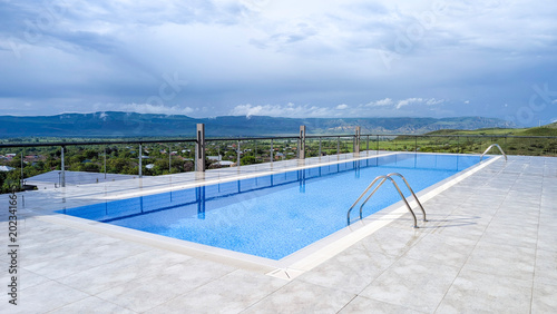Cuadro en lienzo Outdoor infinity swimming pool on a high terrace offering panoramic mountain and