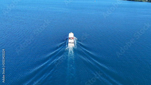 Tablou pe pânză Cruising gracefully across the sparkling blue waters of a serene lake on a sunny