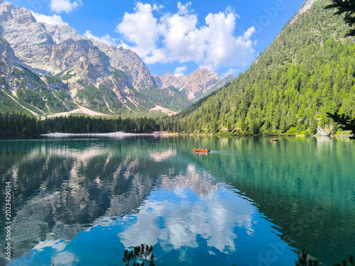 Foto Majestic mountains and serene lake reflect vibrant colors under a bright blue sk