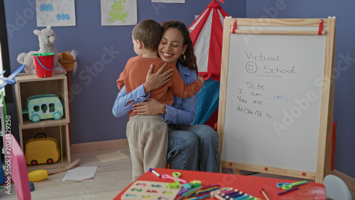 Vászonkép Teacher hugs little boy beside whiteboard and toys in a child learning corner inside a building; gentle comfort