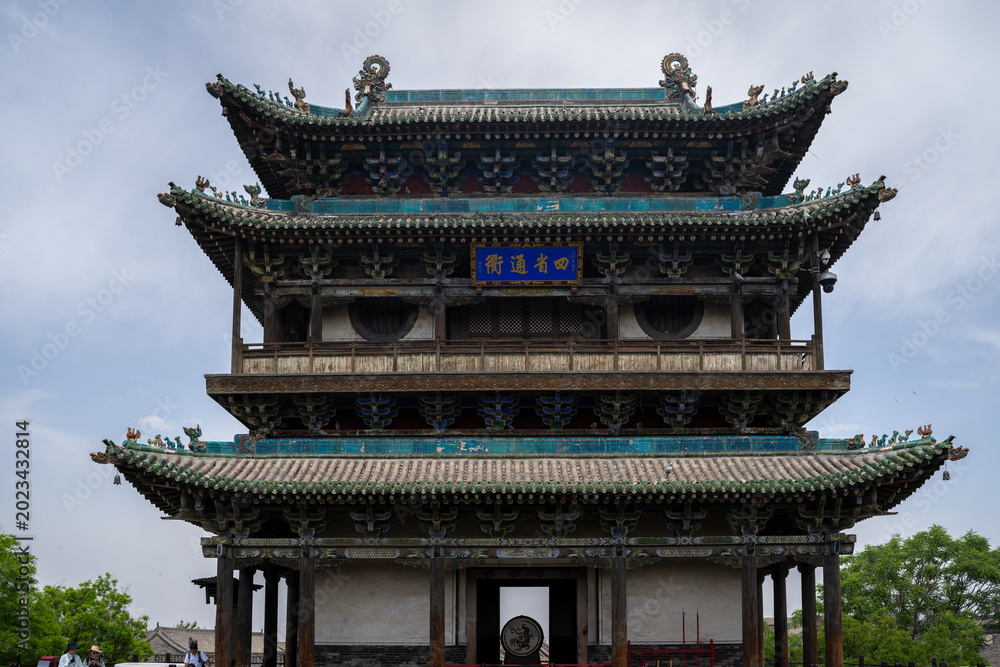 Obraz premium Ancient Chinese tower with ornate roof and blue signage under a cloudy sky