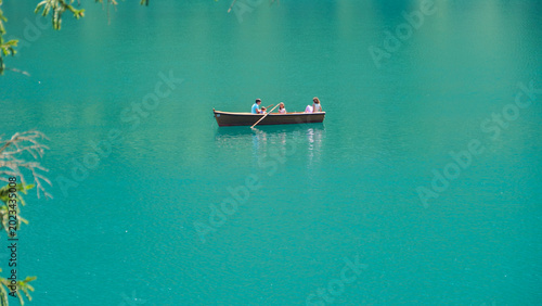 Tableau sur toile Three friends enjoy a serene afternoon rowing on crystal-clear waters surrounded