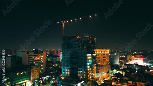 Vibrant Commercial District at Night with Construction Crane – Aerial View of Southeast Asian City