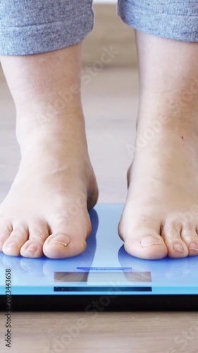 Closeup of a young woman weighing herself on a scale at home