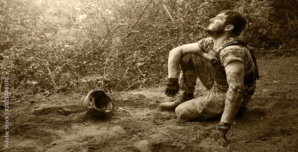 Fototapeta premium Young soldier sitting on the ground