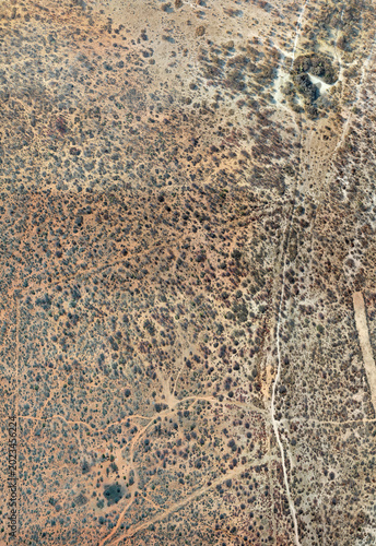 Nadir aerial orthophoto Aerial view of arid landscape with sparse vegetation and dirt tracks