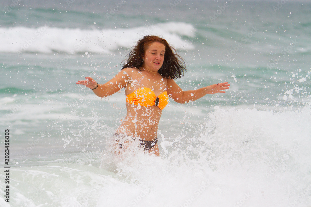 Fototapeta premium Refreshing Summer Swim Female Tourist Wading Through Sea Foam