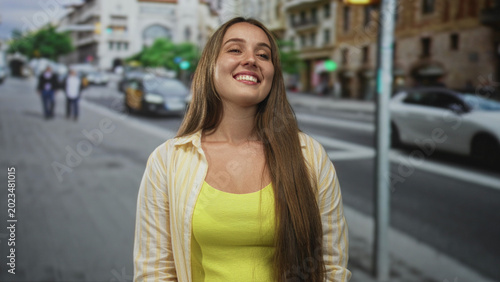 Fotografía Woman smiling on city street crosswalk near taxi, wearing yellow tank top and open shirt; joy confidence wellbeing