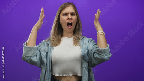 Quadro su tela Woman clenches fists in purple studio wearing white crop top and denim shirt; determination strength