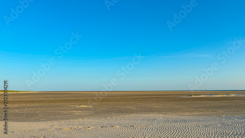 Billede på lærred Horizon line dividing blue sky and sandy ground by sea