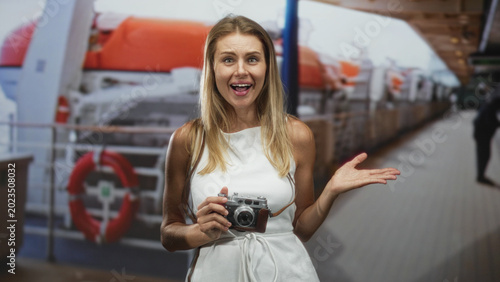 Foto Woman holding vintage camera and gesturing open palm on a studio set with lifeboats and ship deck; travel joy