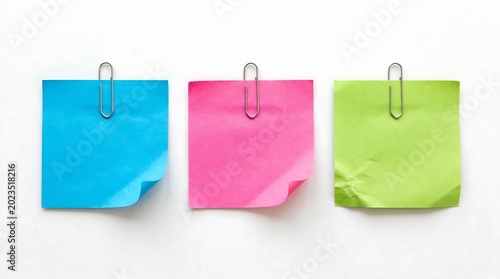 Three colorful sticky notes with paper clips on white background
