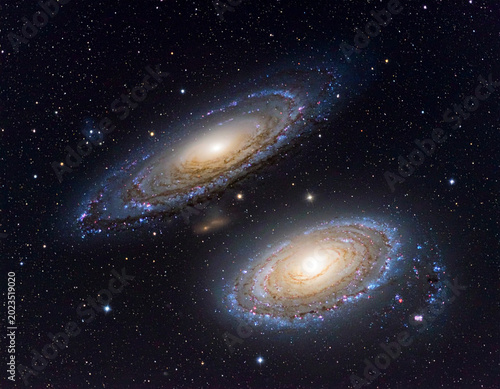 Two galaxies in space showing details of stars and dust at night with a dark background