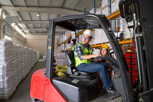 Quadro su tela A warehouse worker navigates a forklift through a warehouse, surrounded by stacked pallets and shelves