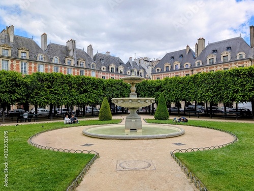 A fountain in Place des Vosges on a cloudy day in Paris, France - May 2026
