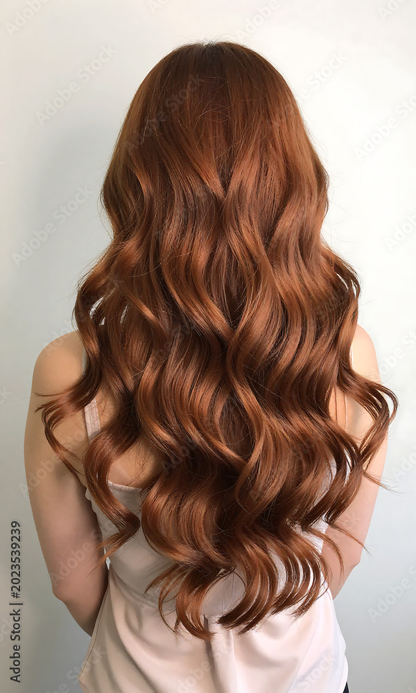 Fototapeta premium female figure stands back facing away camera showcasing long curls styled gentle flowing waves