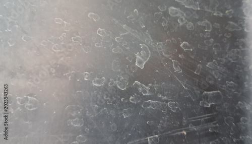 Close-Up Texture of Water Spots and Mineral Stains on Scratched Glass Surface