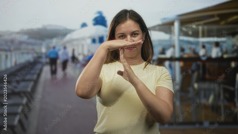 Fototapeta premium Young woman with hands making time out gesture on sunny cruise ship deck near railing; calm pause reflection.