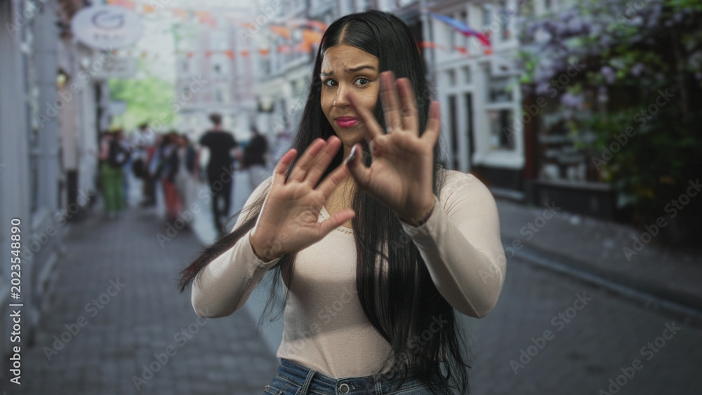 Fototapeta premium Latin woman pinches nose on bustling city street in front of storefronts to block foul odor; disgust.